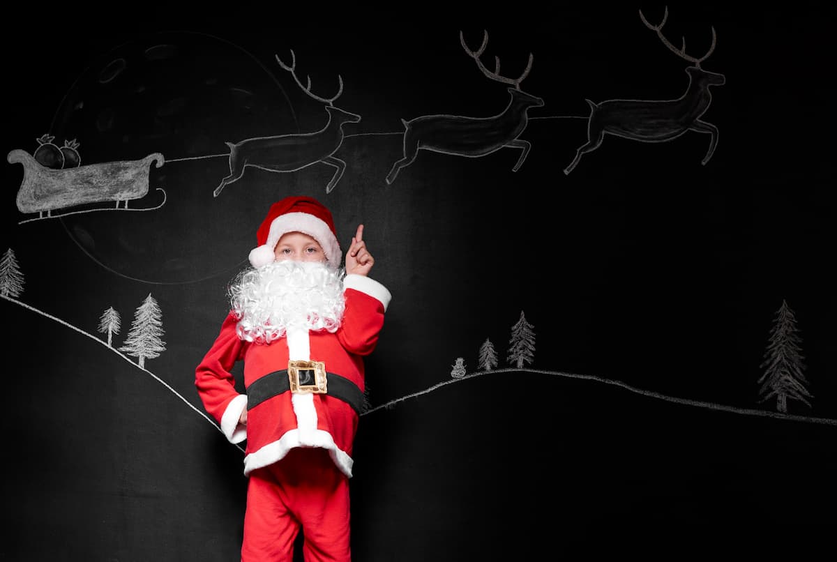 Niño disfrazado de Santa Claus apuntando al fondo